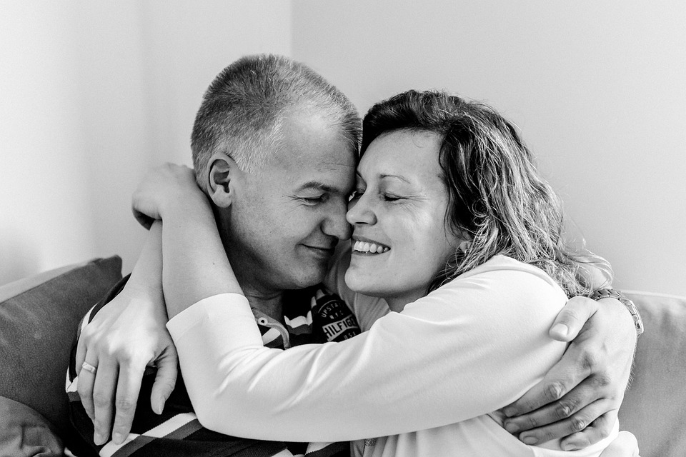 “Pareja madura de unos 55 años abrazada y sonriendo, mostrando bienestar y conexión emocional a pesar de los síntomas de la menopausia.”

