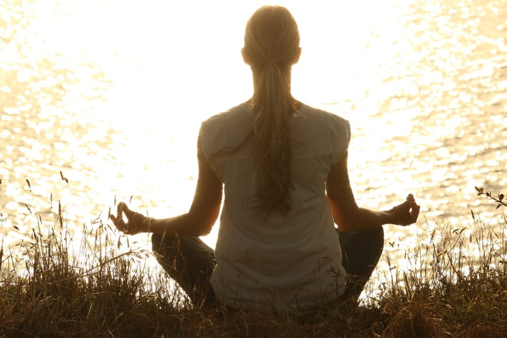 "Mujer meditando al amanecer para reducir los síntomas de la menopausia, practicando yoga al amanecer.